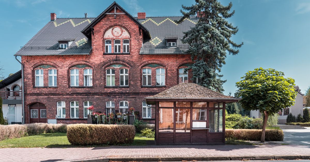 Charming historic brick building with lush greenery under a clear blue sky.